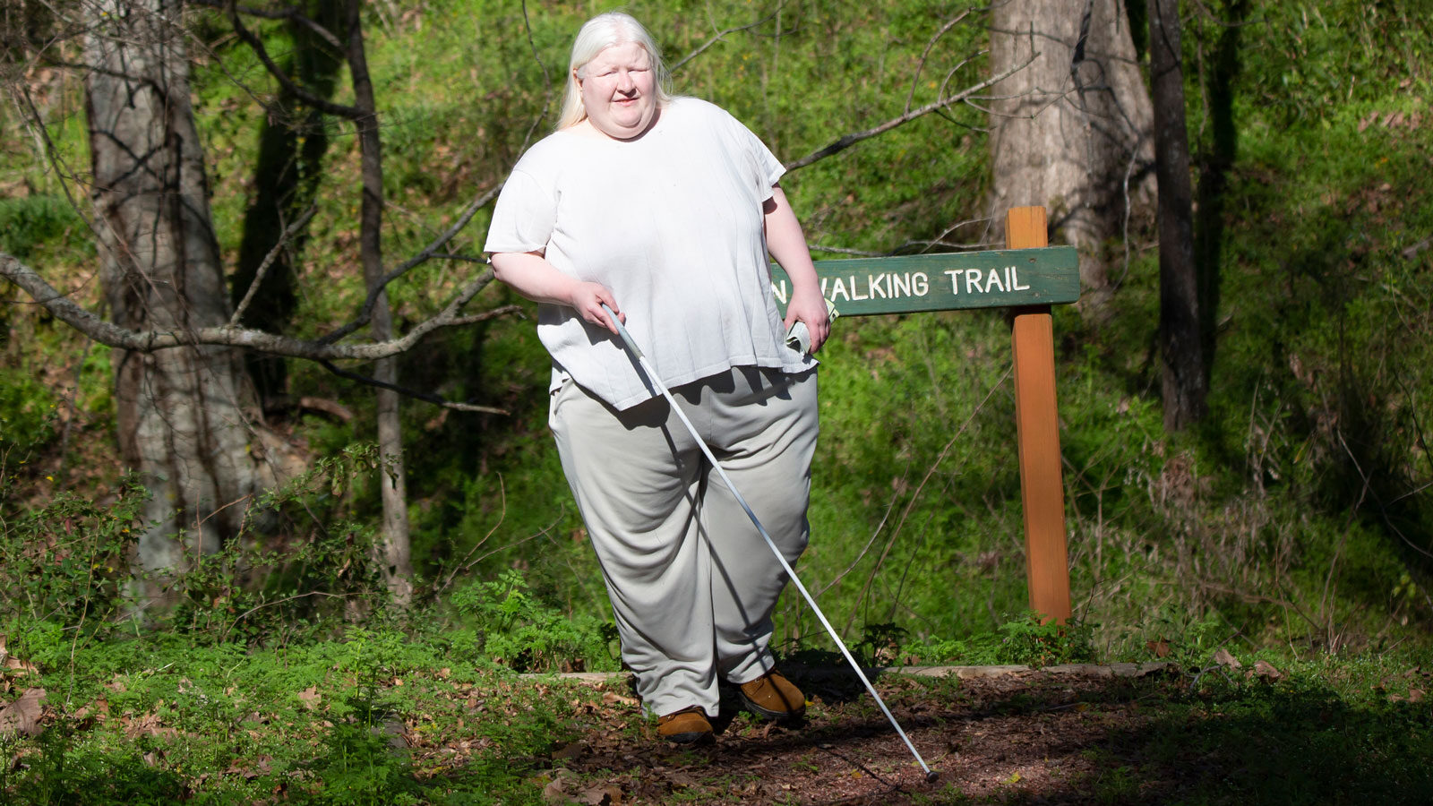 Ginny using her cane to walk down a trail