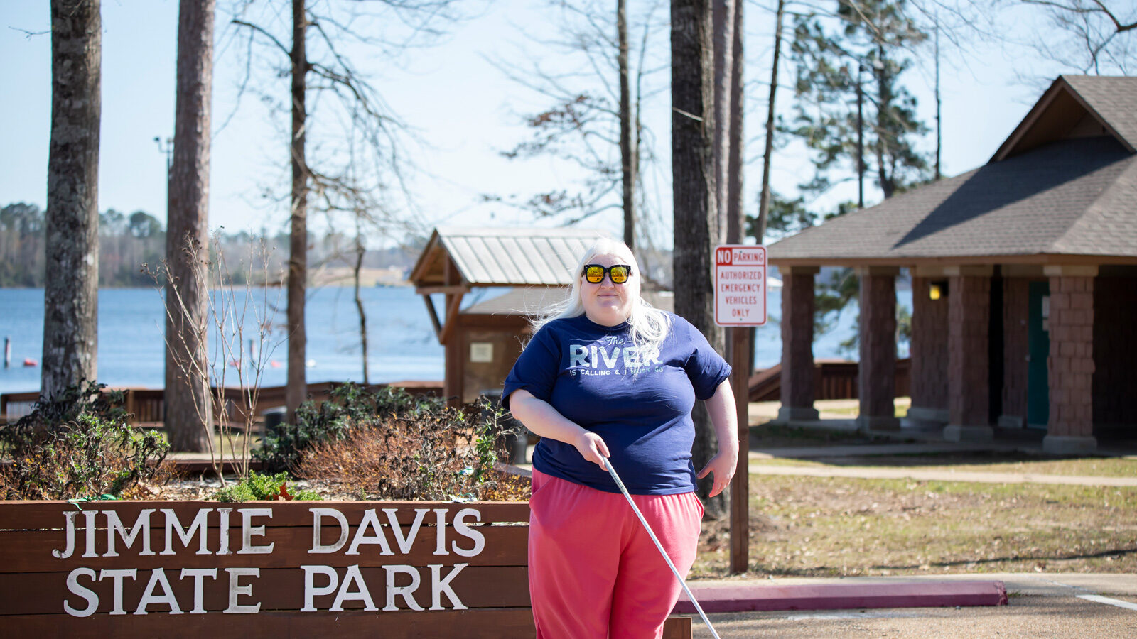 Ginny standing in front of the Jimmie Davis State Park sign with her cane
