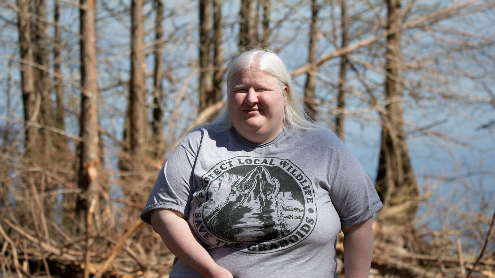 Ginny standing in front of water with lots of trees in it